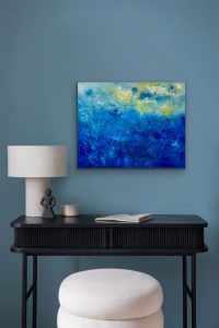 Blue Skies oil abstract by Red is hung on blue wall over small desk.