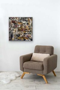 Abstract Painting hung on white wall over casual taupe modern chair